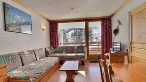 A cozy room with a wooden bench, a table, and a sofa with a patterned cover. - Cozy 4 Pax with Sunny Balcony (Méribel)