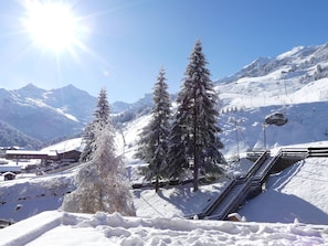 Paesaggio montano innevato con alberi ricoperti di neve e una seggiovia.
