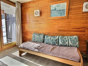 Una habitación con paneles de madera, una cama, un cuadro en la pared y una ventana con cortinas.