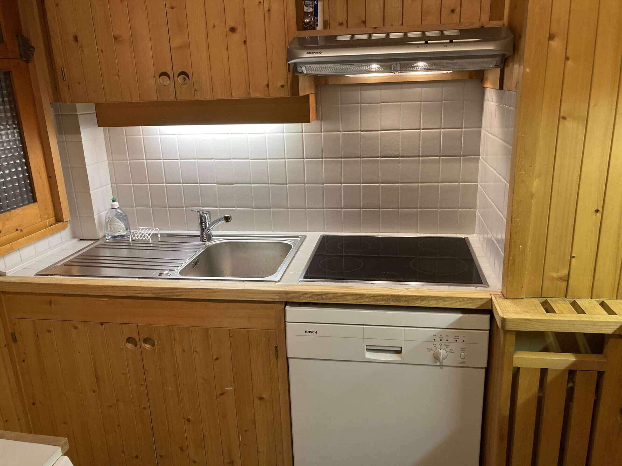 A kitchen with wooden cabinets, a stainless steel sink, a Bosch dishwasher, and a built-in stove.