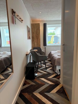 A hotel room with a mirrored wall, a desk, two beds, and a chevron-patterned floor. - Hotel Kløver Es (Rodekro)