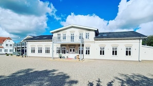 A large, two-story building with a symmetrical facade, a central entrance with a red carpet, and a gravel driveway. - Hotel Kløver Es (Rodekro)