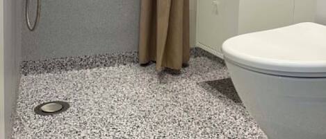 Un baño con inodoro, ducha y lavamanos.