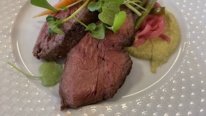 A plate with sliced meat, vegetables, and a green puree. - Hotel Kløver Es (Rodekro)