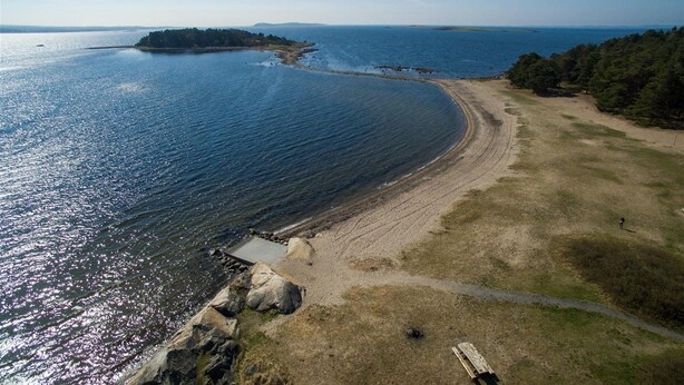 An aerial view of a coastal area with a sandy beach, a rocky shoreline, and a clear view of the ocean. - Larkollen vacation house (Moss)