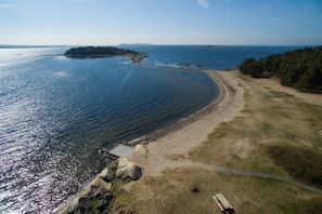 An aerial view of a coastal area with a sandy beach, a rocky shoreline, and a clear view of the ocean. - Larkollen vacation house (Moss)