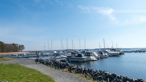 A marina with various boats docked, a grassy area in the foreground, and a clear sky. - Larkollen vacation house (Moss)