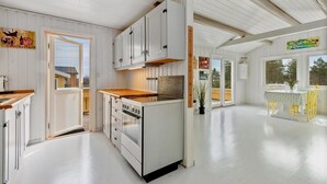 A modern kitchen with white cabinetry, a wooden countertop, and a central island with a sink. - Larkollen vacation house (Moss)