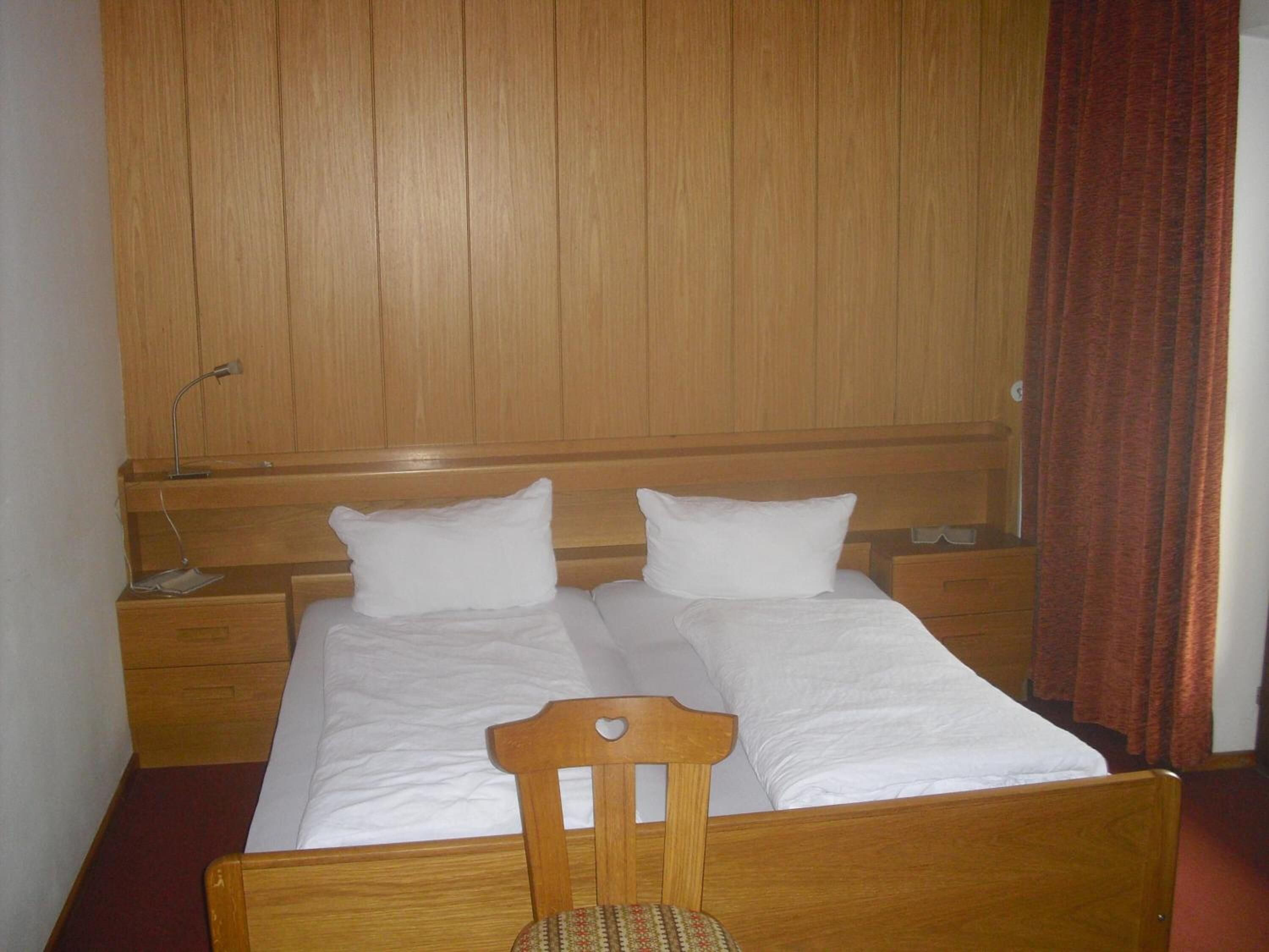 A double bed with wooden headboard and footboard, two bedside tables, and a wooden wardrobe.