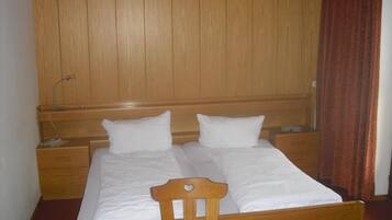 A double bed with wooden headboard and footboard, two bedside tables, and a wooden wardrobe.