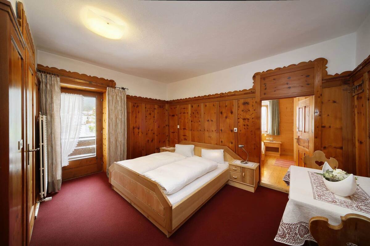 Un dormitorio con paneles de madera, una cama, una mesa con un tazón y una silla.