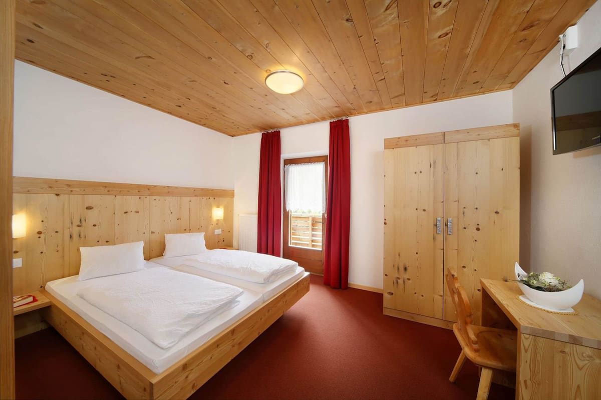 Un dormitorio con paneles de madera, una cama, un escritorio y un televisor.