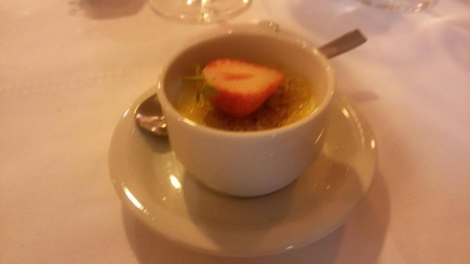 A bowl of soup with a slice of tomato on a saucer.