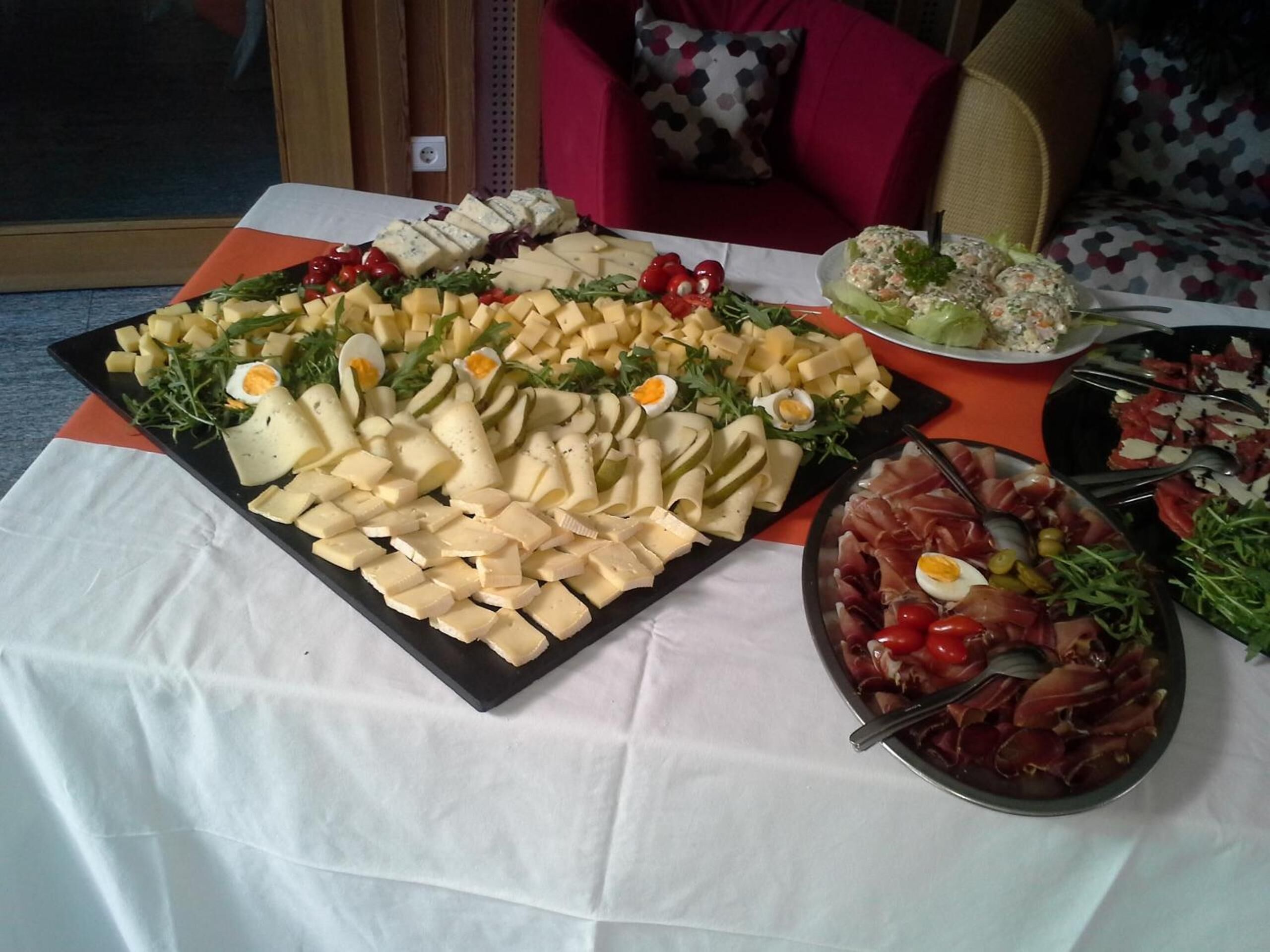 Una mesa de buffet con diversos quesos, carnes y ensaladas.