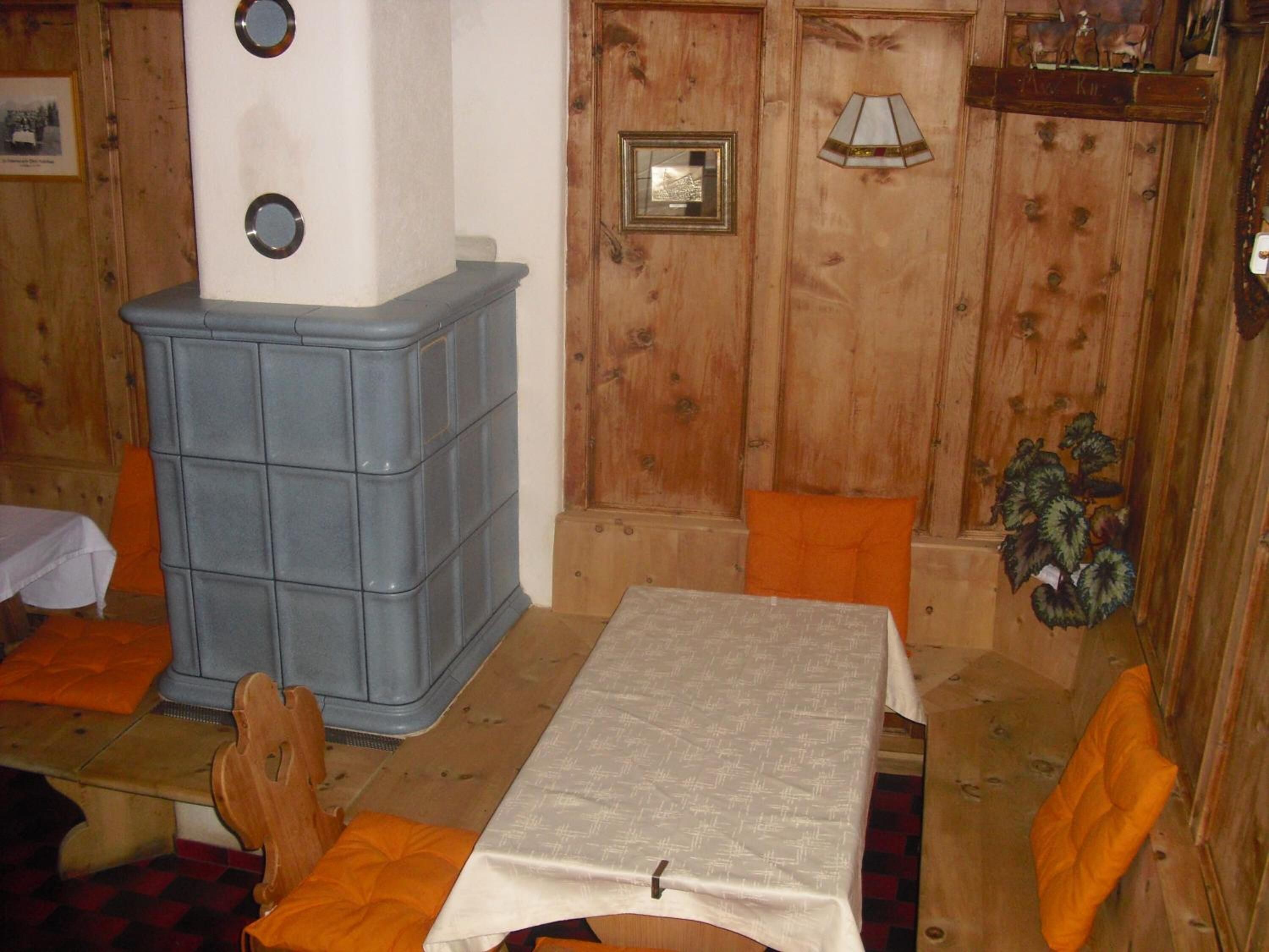 A room with a wooden wall, a blue cabinet, a table with a white tablecloth, and orange chairs.