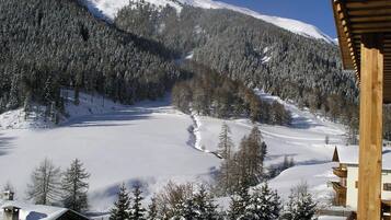 Een besneeuwd berglandschap met een houten hutje op de voorgrond.