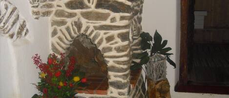 A stone wall with a decorative archway, a potted plant with red flowers, and a wooden door.
