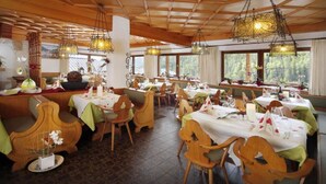 Een restaurant met houten meubels, gedekte tafels en grote ramen met uitzicht op het omliggende landschap.