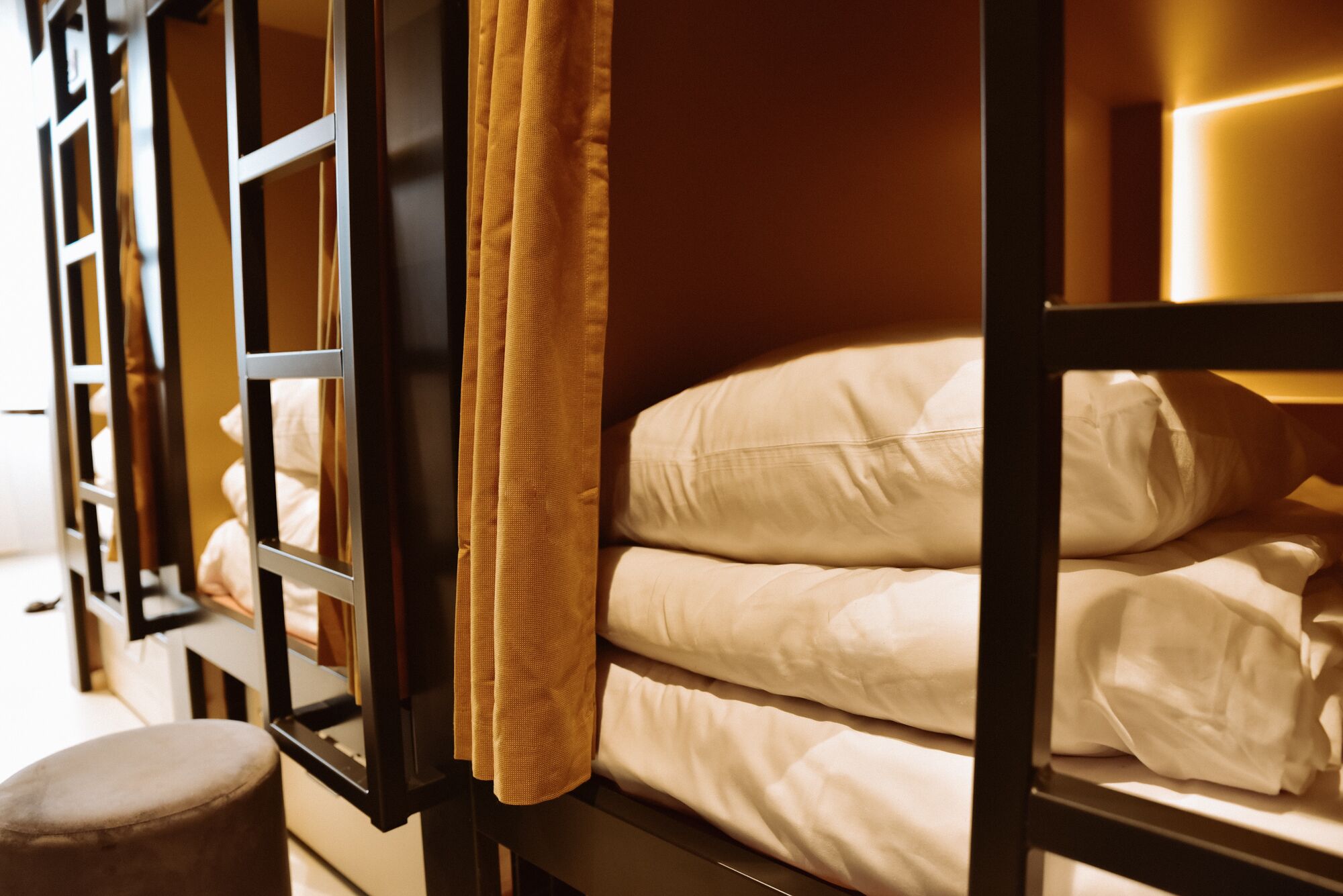 A bunk bed with white bedding and a curtain.