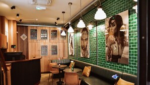 Un bar acogedor con paredes de madera, un revoque de azulejos verdes y un rincón con sofás y mesas.