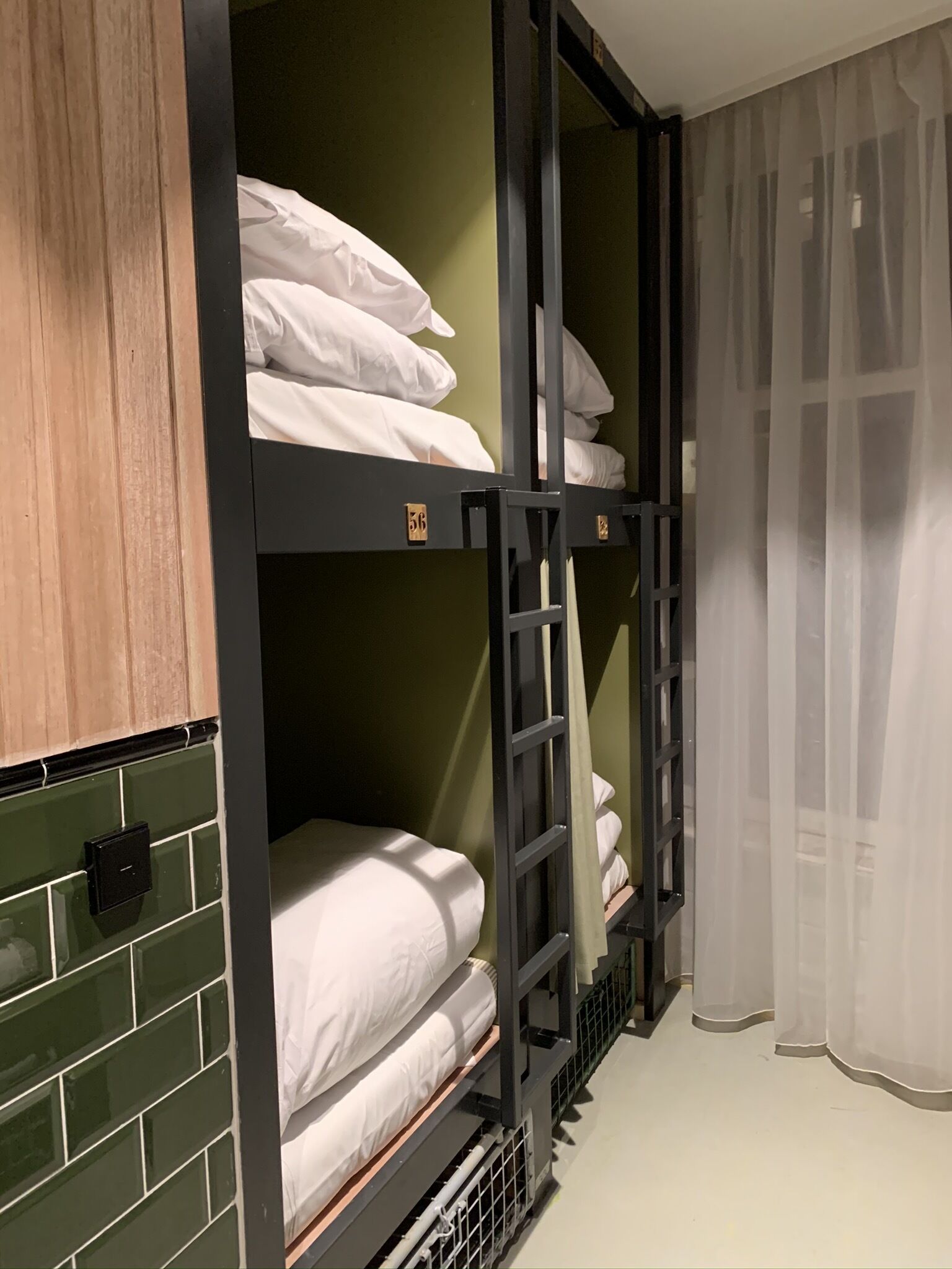 Une chambre avec des lits superposés, des murs verts, une armoire en bois et un rideau.