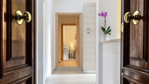 A hallway with wooden doors, a white tiled floor, and a plant on the wall. - Rome Central Rooms Guest House (Rome)
