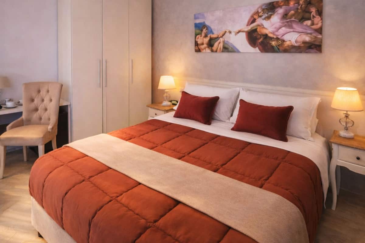 A bedroom with a large bed, a chair, a desk, and a wardrobe.