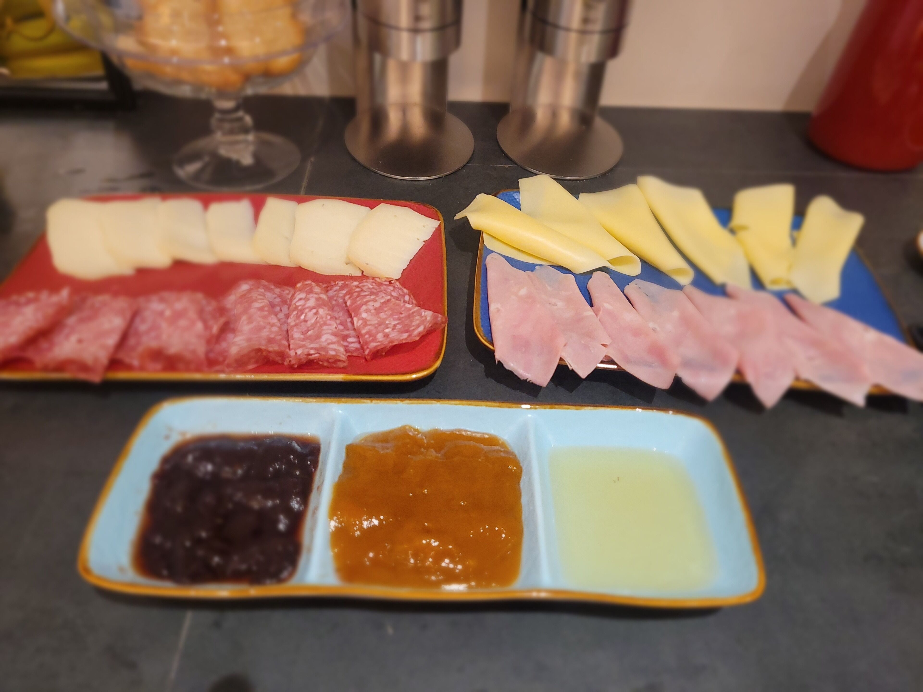 Una mesa con diversos alimentos, entre ellos embutidos, quesos y salsas.