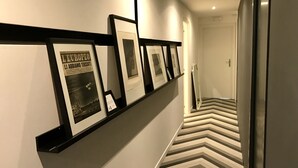 A hallway with a black-framed photo display on the left and a zigzag patterned floor. - Gallery (Rome)