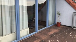 A residential building with a sliding glass door leading to a covered patio area. - Hotel am Kamp (Laatzen)