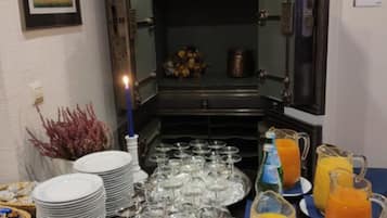 A buffet setup with plates, glasses, and juice pitchers on a table.