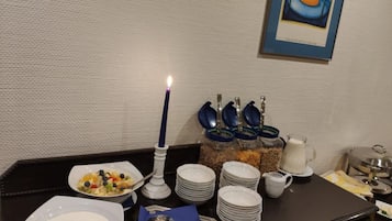Ein Frühstücksbuffet mit Tellern, Schüsseln und einer Kerze auf einem Tisch.