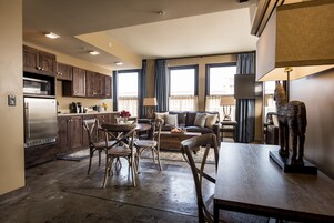 Una cocina moderna con armarios de madera, un refrigerador de acero inoxidable y un comedor con mesa y sillas de madera.