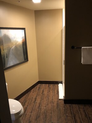 A bathroom with a toilet, a framed picture on the wall, and a towel rack. - Frontier Hotel Pawhuska (Pawhuska)
