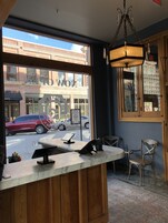 Interior de un restaurante con mostrador de mármol, paneles de madera y vista a la calle.