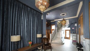 Eine weitläufige Lobby mit einer Treppe, einer hölzernen Bank und zwei Lampen.