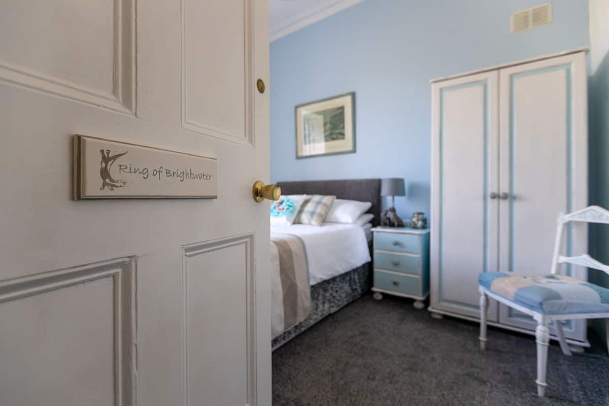 A bedroom with a bed, a nightstand, a wardrobe, and a chair.