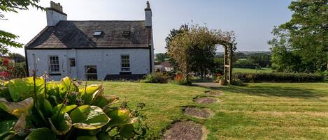 A white house with a stone pathway leading to a wooden archway.