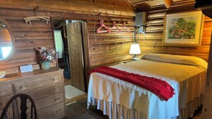 Un dormitorio tipo cabaña de madera con una cama, cómoda y espejo.