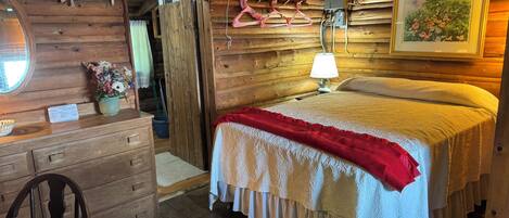 A wooden cabin bedroom with a bed, dresser, and a mirror.