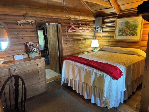 Une chambre dans une cabane en bois, avec un lit, une commode et un miroir.