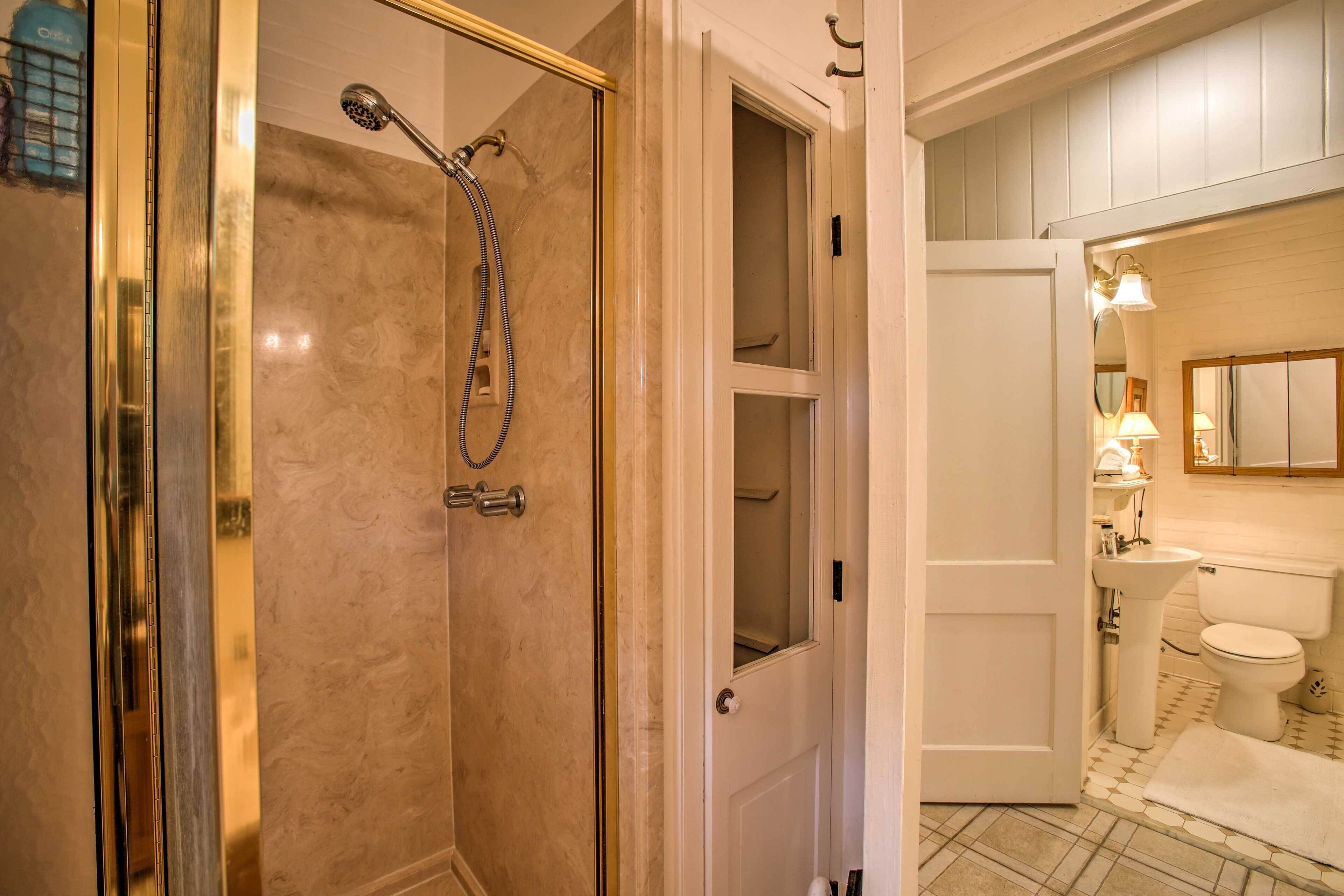Een badkamer met douche, toilet, wastafel en spiegel.