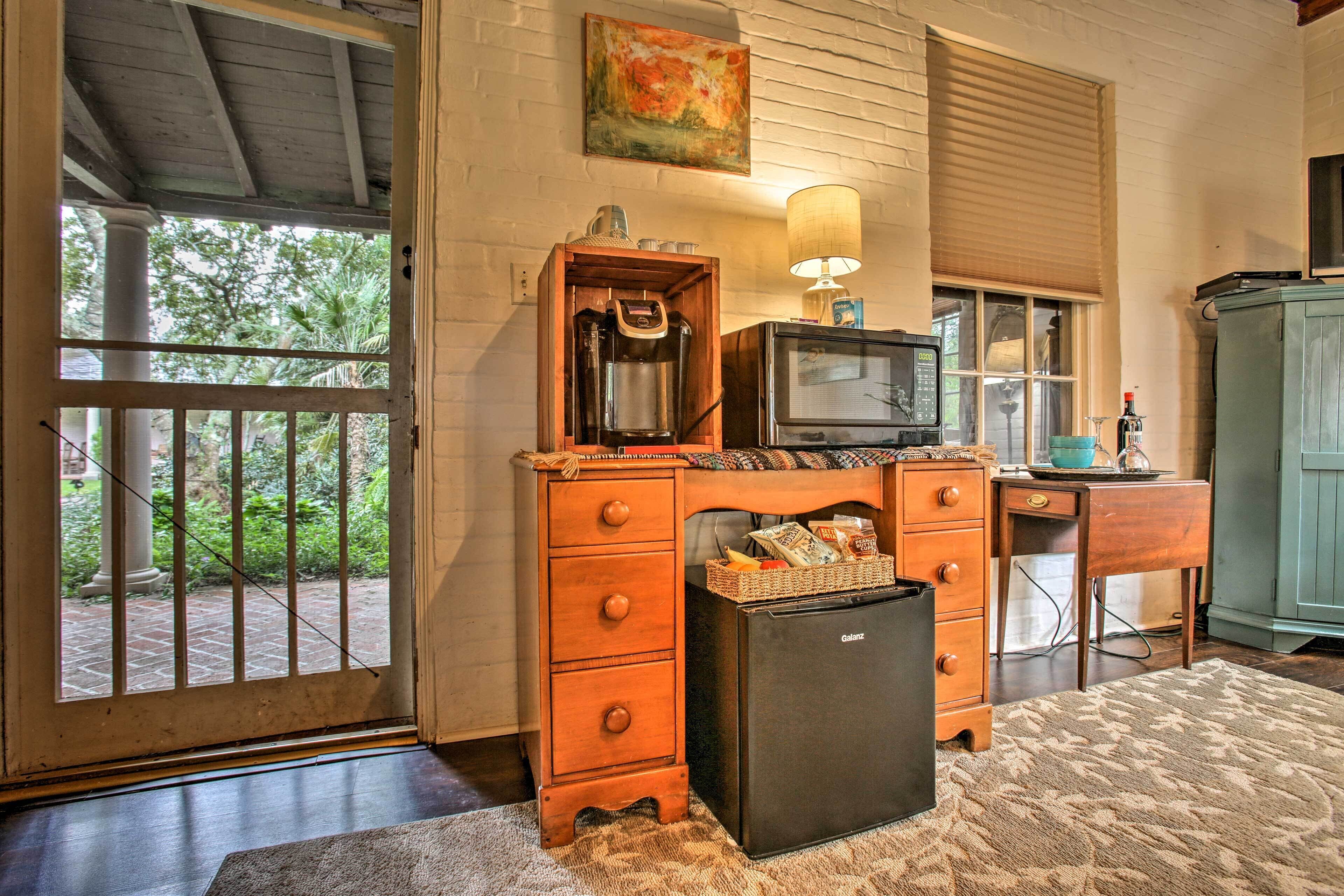 A compact kitchen with a refrigerator, a coffee maker, a television, and a wooden cabinet.
