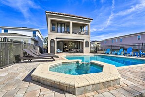 Une maison à deux étages avec une piscine, des chaises longues et un patio clos.