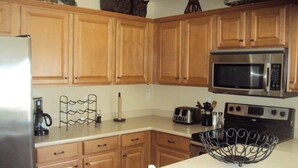A kitchen with wooden cabinets, a stainless steel refrigerator, a microwave, a toaster, and a sink. - *SUMMER SPECIALS** Scenic Golf Course 3 Bed Home w/ Private Pool and Hot Tub (Queen Creek)