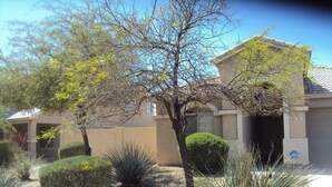 A residential area with a house, a well-maintained garden with various shrubs and a tree, and a clear sky. - *SUMMER SPECIALS** Scenic Golf Course 3 Bed Home w/ Private Pool and Hot Tub (Queen Creek)