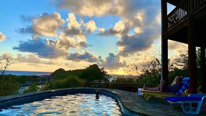 A swimming pool with a view of the sea and mountains, surrounded by greenery and a wooden deck with lounge chairs. - Zandoli Villa
Simply Awesome Views (Cap Estate)
