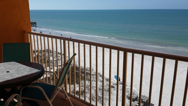 A balcony with a view of the beach and ocean.