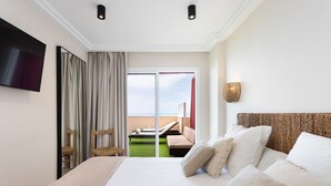 A hotel room with a large bed, a flat-screen TV, a balcony with a view, and a wicker headboard. - APARTMENT A few meters from a black sand beach. (Santiago del Teide)