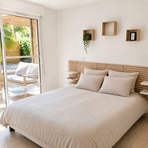 Ein Schlafzimmer mit Bett, Nachttischen, einem Fenster und Blick ins Freie.